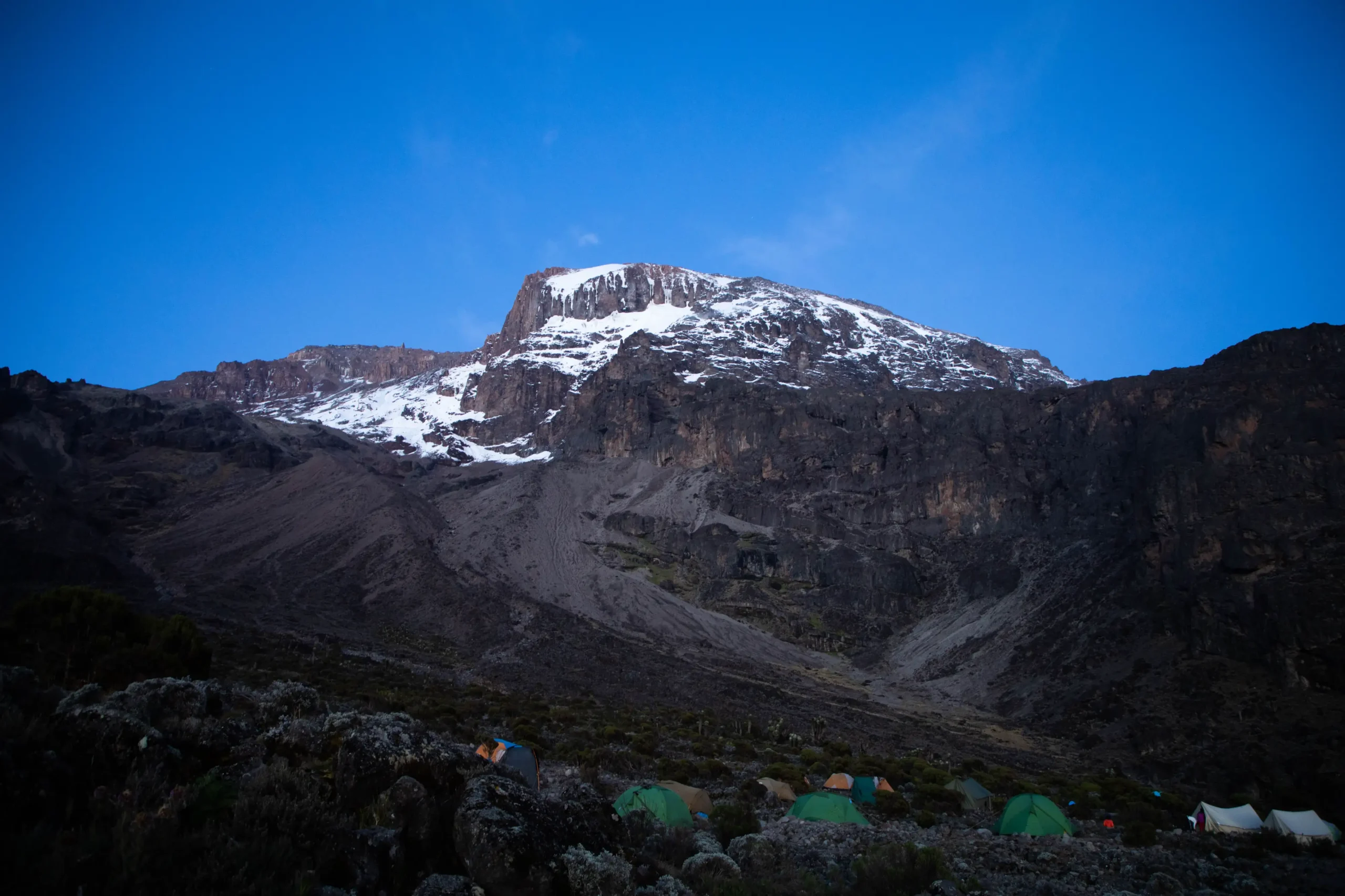 Camping tents at Kilimanjaro base camp during climbing season with mountain backdrop