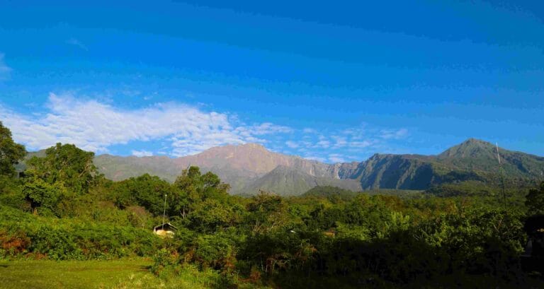 Climbers reaching Mount Meru Socialist Peak at sunrise with Mount Kilimanjaro in background