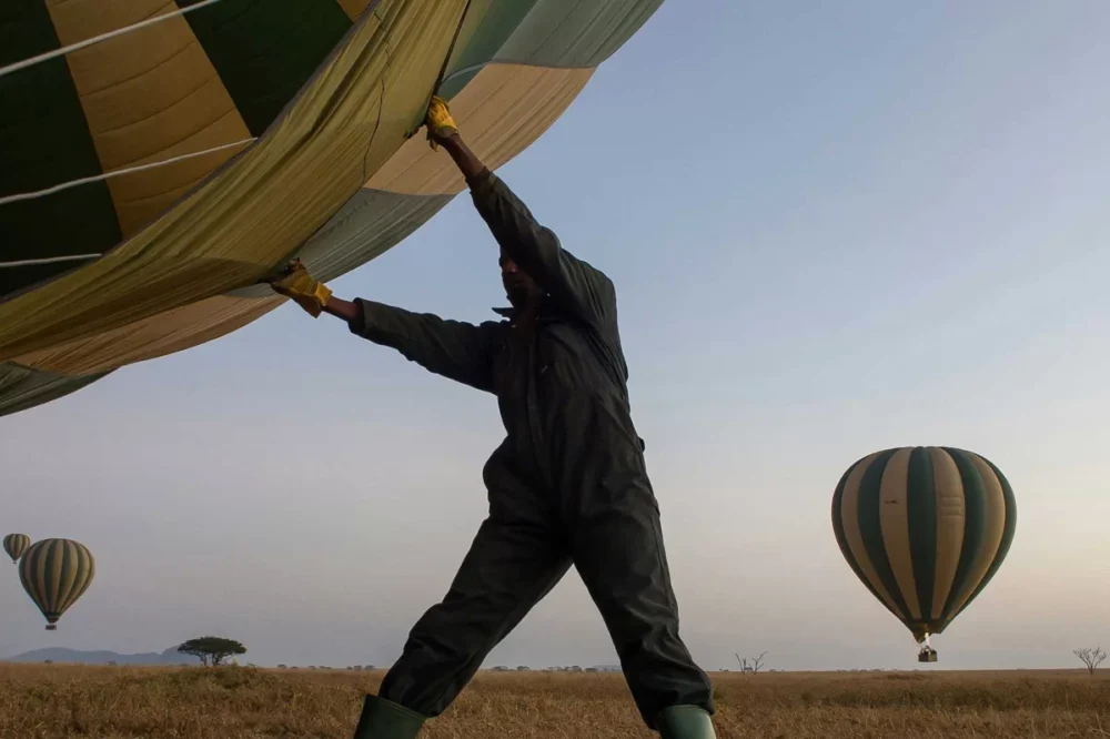 Ground crew inflating hot air balloon at dawn on the Serengeti, Tanzania