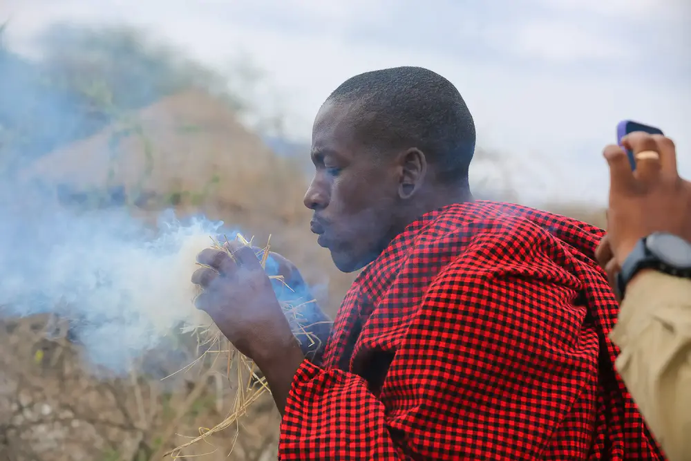 Alt text: Maasai warrior demonstrating traditional fire-making techniques using natural materials in the Ngorongoro Conservation Area, Tanzania.